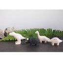 Set of dinosaur figurines on a dark surface with green leaves in the background
