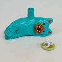 Blue clay cat laying next to a tray with sake on it.