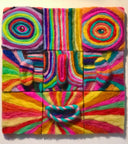 Assembled 3 x 3 grid of felt squares, all with rainbow coloring and line art containing different cartoon face components. Combined, creates a face with wide swirling eyes and a small open mouth smile.