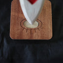 Whittled wooden sculpture of a knife, turned down and onto a stand. The blade of the knife is white with red arrow patterning and the handle is leather bound.