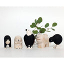 Set of wooden animal figurines on a white surface with green leaves in the background