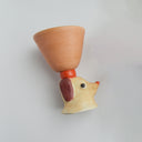 Ceramic orangish pink cup with a brown floppy eared dog as a handle.