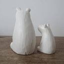 Two white wooden polar bear figurines on a wooden surface with a plain background