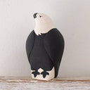 Stylized black and white bird figure on a wooden surface with a light gray background