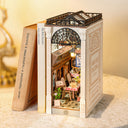 Miniature model of a book with a detailed interior scene in side of it, resembling an arcade dating setup.