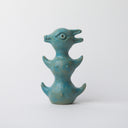 Turquoise colored ceramic sculpture of a tall animal like creature, stacked up like a totem pole with its rounded stomach at the bottom, rounded chest in the middle and rounded head with a small snout and 2 pointed ears as the top.
