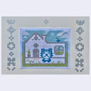 Small embroidery of a cat sitting in a white house.