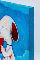 Colorful illustration of Snoopy, sitting atop of his red dog house reading a book, a pile of books sits nearby. The sky is blue with blue clouds. Close up shot shows color detailing.