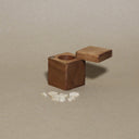 Wooden cube with a hole on a beige background Tiny little wooden objects are set to the side.