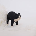 Wooden figurine of a black and natural wood color cat with an arched back.
