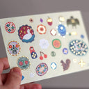 Postcard with many colorful buttons and charm illustrations on it.