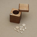 Wooden cube with a hole on a beige background Tiny little wooden objects are set to the side.