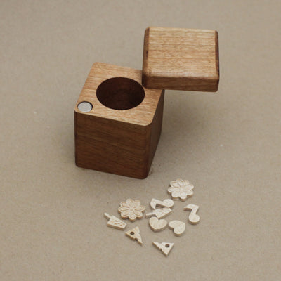 Wooden cube with a hole on a beige background Tiny little wooden objects are set to the side.