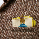 Folded handkerchief in a jacket pocket, with a yellow embroidered alien peeking out.