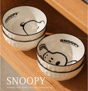 Set of 4 bowls with graphics of Snoopy, sitting or laying. Stacked in piles of 2.