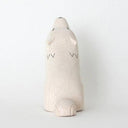 White wooden figurine of a wolf, with its head tilted back and its eyes closed. It howls with its mouth open.