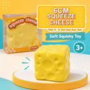 A yellow cheese-shaped squishy toy displayed in front of its retail box on a white platform, with colorful text overlays reading '6CM SQUEEZE CHEESE', 'Soft Squishy Toy', and '3+'.