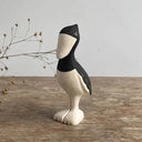 Decorative figure of a shoebill bird, standing on a wooden surface with a gray background