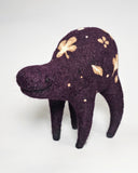 A handmade felted wool animal figure in deep purple with cream-colored shamrock and dot patterns, standing against a plain white background.