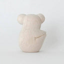 White wooden figurine of a koala, smiling with a cute cartoon facial expression.