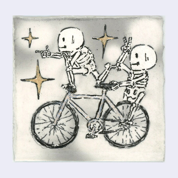 Drawing of 2 small cartoon skeletons riding a tandem bike with gold sparkles.