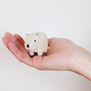 Small white capybara figurine held in a hand against a plain background