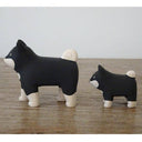 2 small wooden figurines of black and white shiba inu dogs, one is slightly smaller than the other.