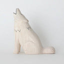 White wooden figurine of a wolf, with its head tilted back and its eyes closed. It howls with its mouth open.