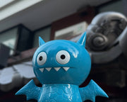 Figurine of Uglydoll Ice-Bat, with wide eyes and fanged teeth. It has horns, wings and scaled body.