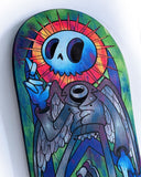 Close up of a colorful painting on a skateboard deck - a blue skeleton character with an orange ray of light around its head.