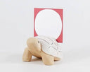 Wooden figurine of a turtle with a patterned shell and a card being held upright in its shell.
