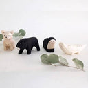 Set of small animal figurines on a white surface with green leaves.