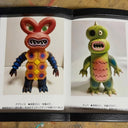 Two colorful monster figurines in an open book on a textured surface.