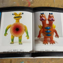 Open book showing two colorful toy figures on a textured surface.