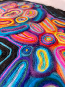 Artwork made out of tufted felt on flat, canvas like surface of an abstract portrait with many colors. Close up.