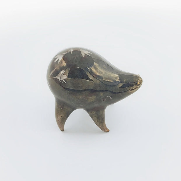 Rounded brownish silver ceramic sculpture of a quadruped with short legs and small gold eyes over a goofy open mouth smile. Its body features a subtle silver flower pattern.