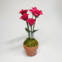Sculpture of pinkish red roses coming out of a small pot. The inside of the roses are tiny creatures, looking up.