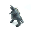 Ceramic sculpture of a large dark gray Godzilla character with a thicker, large body and a curled tail. It has gray glazed spikes along its back and has its mouth open wide, showing small sharp white teeth.
