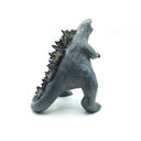 Ceramic sculpture of a large dark gray Godzilla character with a thicker, large body and a curled tail. It has gray glazed spikes along its back and has its mouth open wide, showing small sharp white teeth.