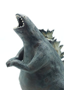 Ceramic sculpture of a large dark gray Godzilla character with a thicker, large body and a curled tail. It has gray glazed spikes along its back and has its mouth open wide, showing small sharp white teeth.