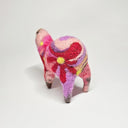 Needle felted wool sculpture of a pink rounded body quadruped creature with an open mouth, goofy smile and small black dot eyes. Its body contains a pink, purple and red retro swirl and floral pattern.