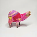 Needle felted wool sculpture of a pink rounded body quadruped creature with an open mouth, goofy smile and small black dot eyes. Its body contains a pink, purple and red retro swirl and floral pattern.