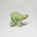 Needle felted wool sculpture of a light green rounded body quadruped creature with a cute smile and small black eyes. It has red, orange and yellow poppy flowers on its body.