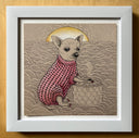 A framed artwork featuring a small chihuahua wearing a pink patterned sweater, sitting in front of a yellow sun over a textured landscape. The print is housed in a white frame and displayed against a warm beige background.