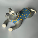 Ceramic dog figurine wearing a blue vest with yellow spots on a gray background