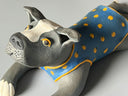 Ceramic dog figurine wearing a blue vest with yellow spots on a gray background