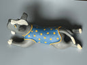 Ceramic dog figurine wearing a blue vest with yellow spots on a gray background