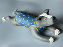 Ceramic dog figurine wearing a blue vest with yellow spots on a gray background