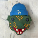 Green animal head mask with blue cap featuring 'LA' logo on a wooden surface