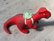 Ceramic sculpture of a red dinosaur wearing a green backpack that says 'GR Japantown"